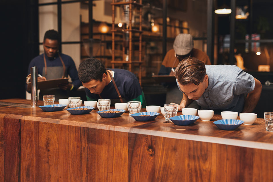 Men participating in cupping session smelling coffee blends