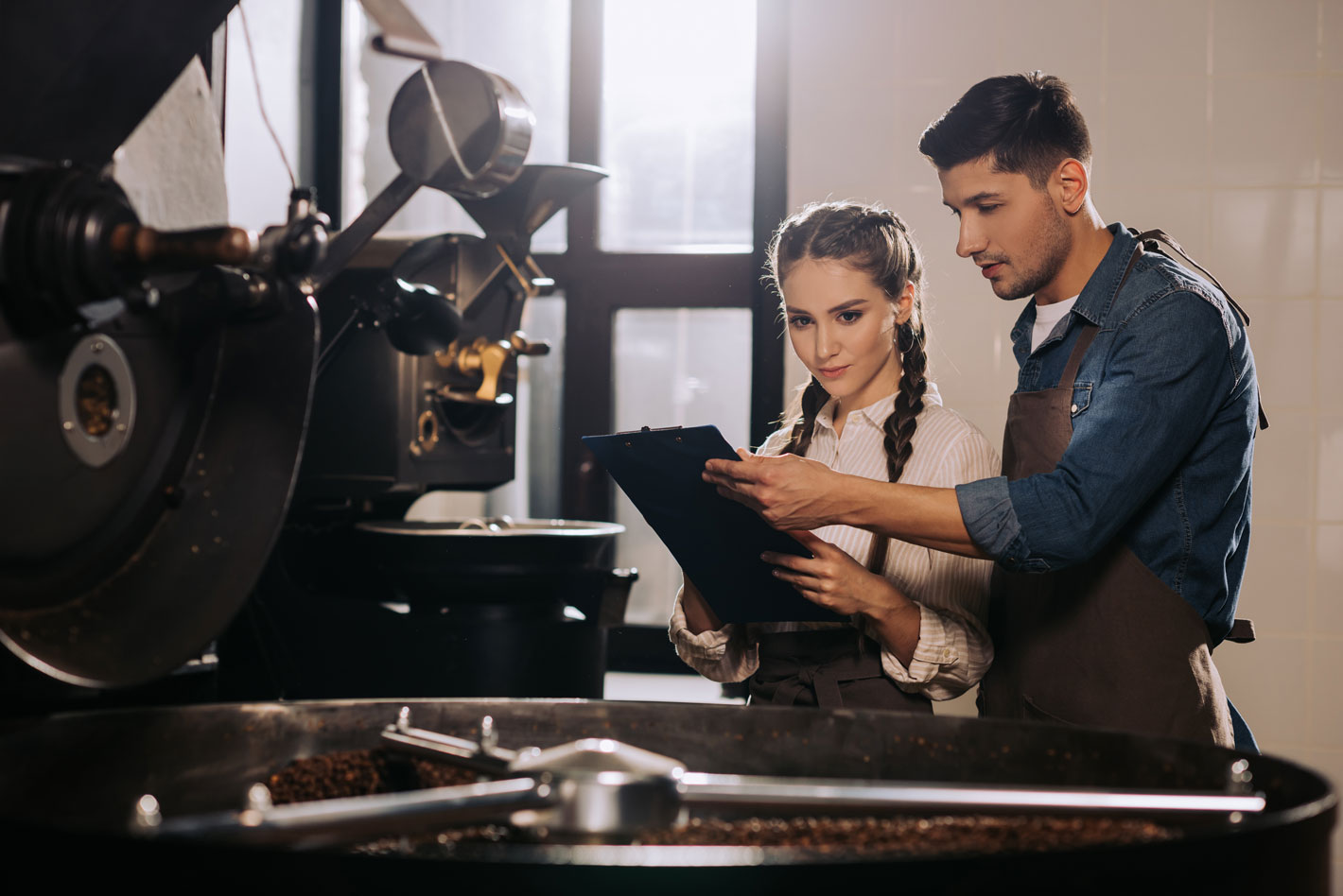 Man and woman in front of roasting equipment