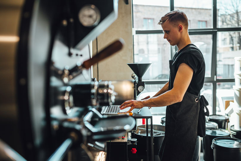 Man with laptop at roasting equipment