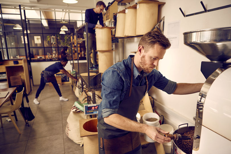 Three men working together in roastery