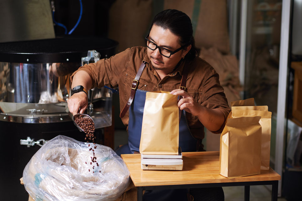 Man weighing beans into individual coffee bag