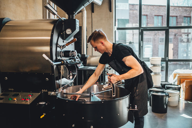 Man cleaning coffee roasting equipment